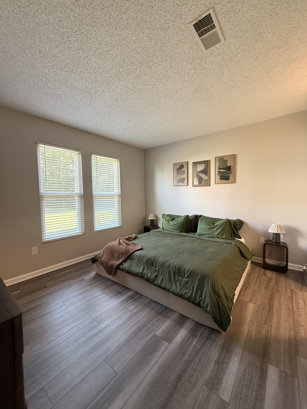 Bedroom with green bedding and large windows